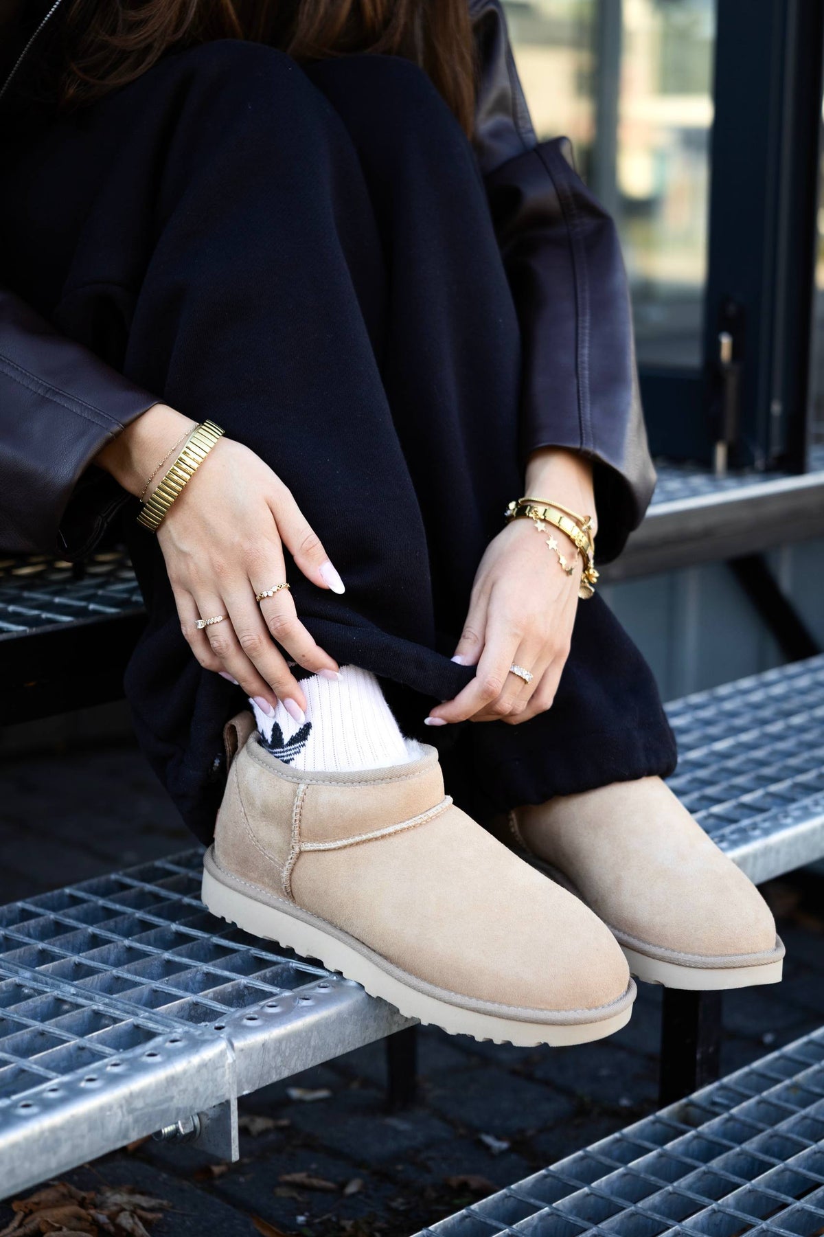 UGG Classic Ultra Mini Sand z białymi skarpetami na metalowych schodach